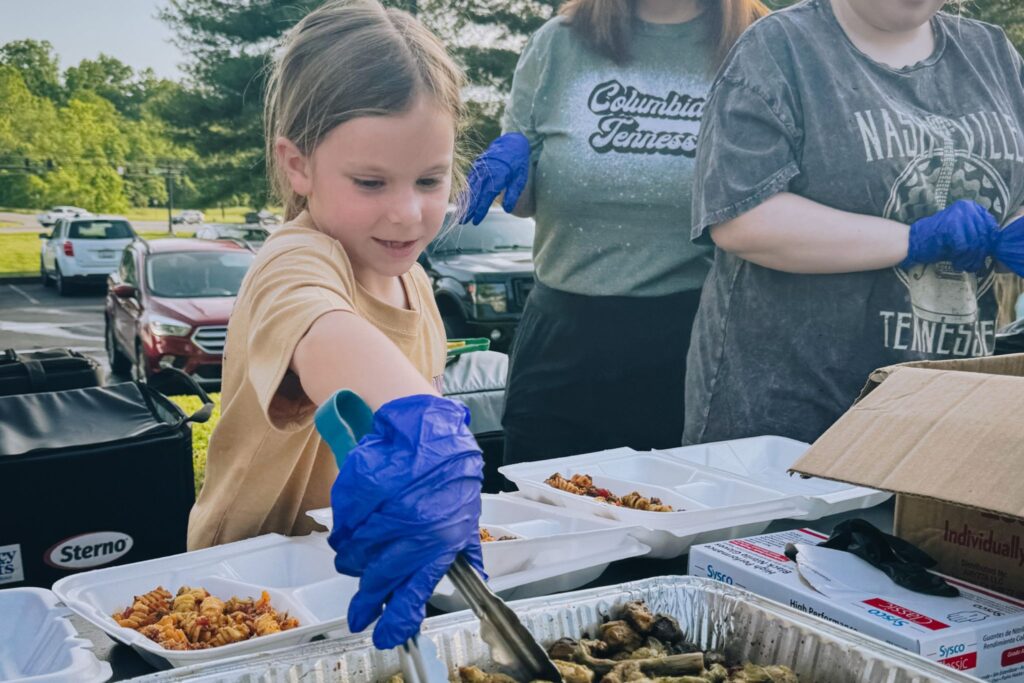 Girl helping serve a hot meal to tornado survivors at Columbia, TN