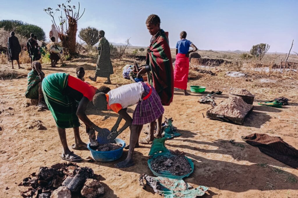 Women in Kaabong, Uganda, gathering the remains of their homes after devastating fires.