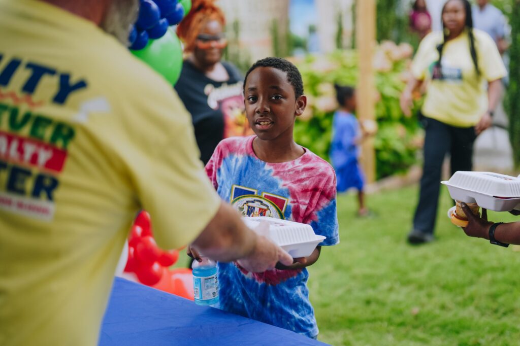 A boy receiving a hot meal at the 2025 Back-to-School Block Party