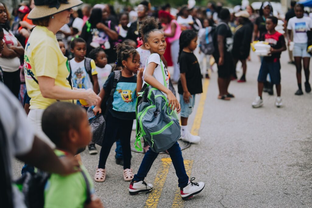 Children receiving meal-filled backpacks at the 2025 Back-to-School Block Party 