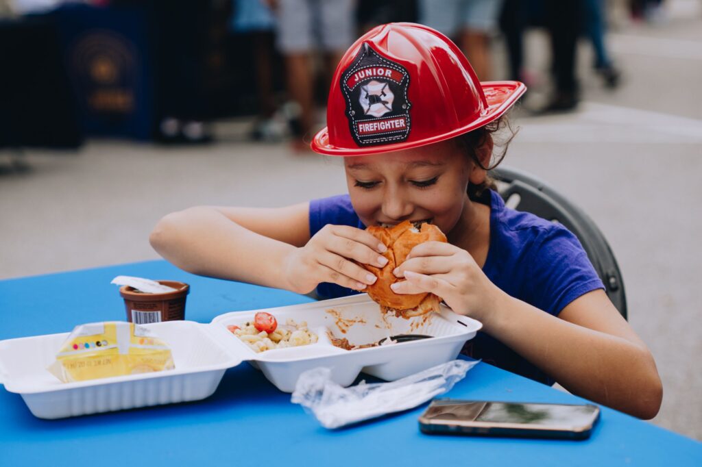 A girl enjoying a hot meal at the 2025 Back-to-School Block Party