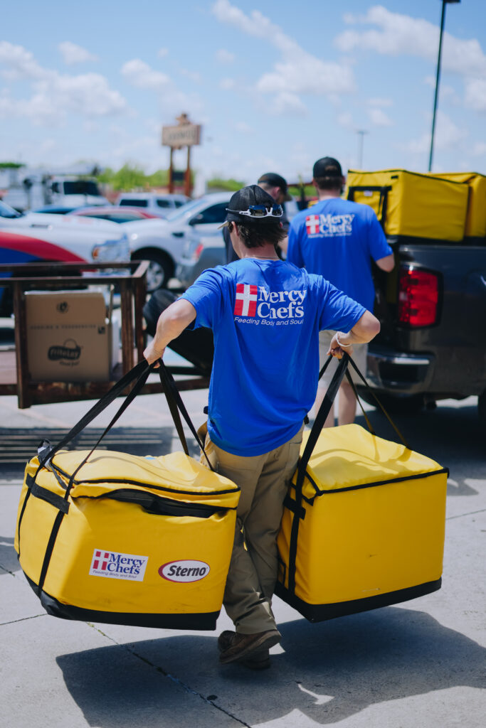 A Mercy Chefs volunteer carries Sternos holding hot meals