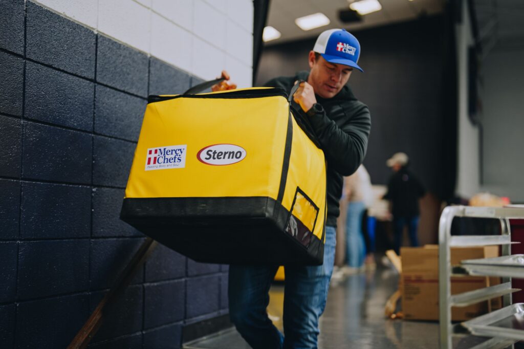 A Mercy Chefs staff member carries a Sterno bag filled with hot meals