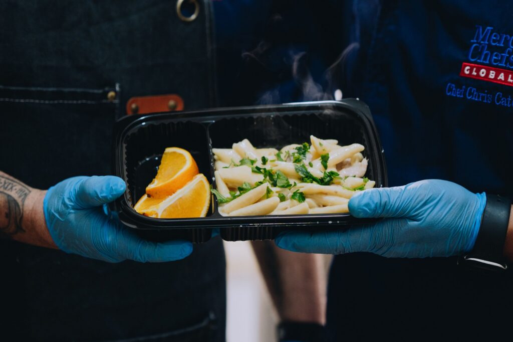 A warm plate of pasta and sliced oranges, prepared by Mercy Chefs