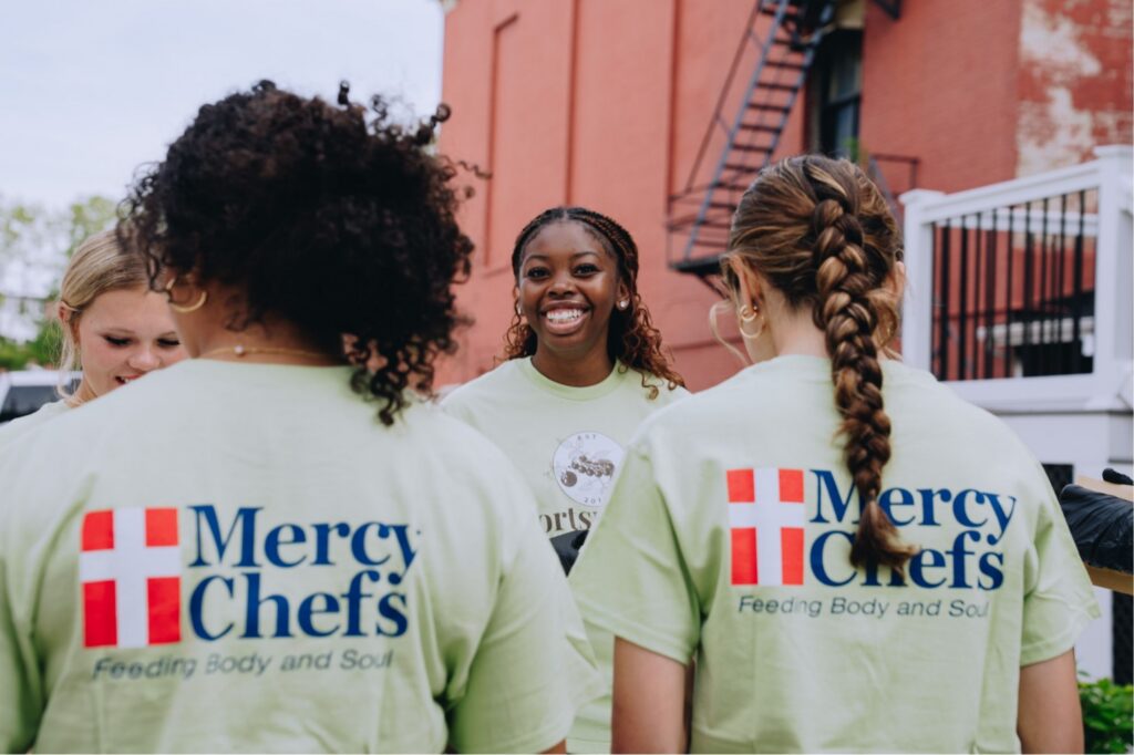 A volunteer at the Mercy Chefs Portsmouth Community Kitchen smiles as she helps prepare a meal